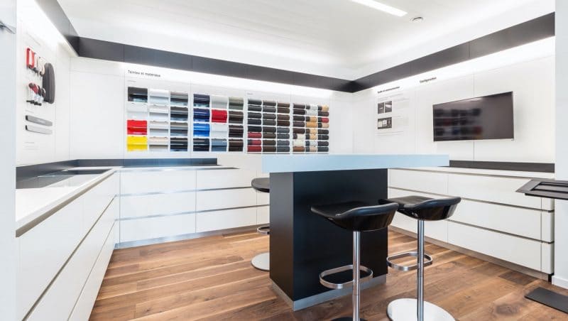 De showroom van edibo, waar in het midden een een zwarte tafel met glazen blad staan, om industriebouw opdrachten te bespreken met klanten. Aan de witte muren hangen verschillende stalen en kleuren.