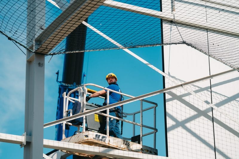 Een medewerker van edibo staat op een hoogtewerker en is bezig deze te verplaatsen. Hij houdt daarbij rekening met het (val)net dat boven hem gespannen is.