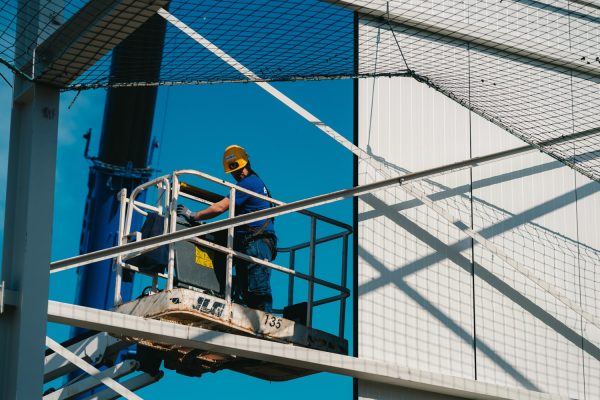 Een medewerker van edibo staat op een hoogtewerker op een industriebouwwerf.